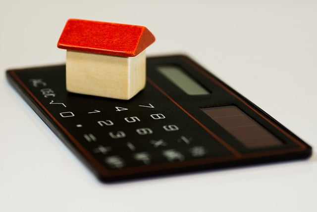 casinha de madeira em cima de uma calculadora representando o índice que corrige aluguéis